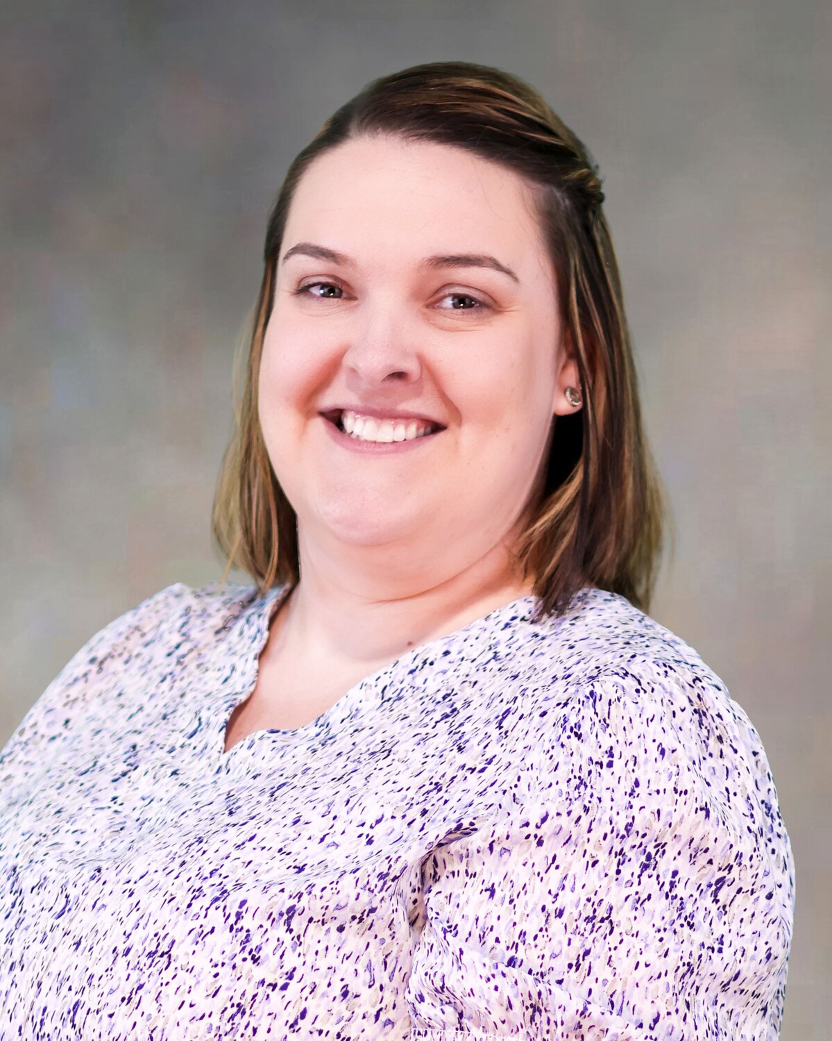 Person wearing a light-colored blouse with a subtle purple pattern, posed against a neutral background.
