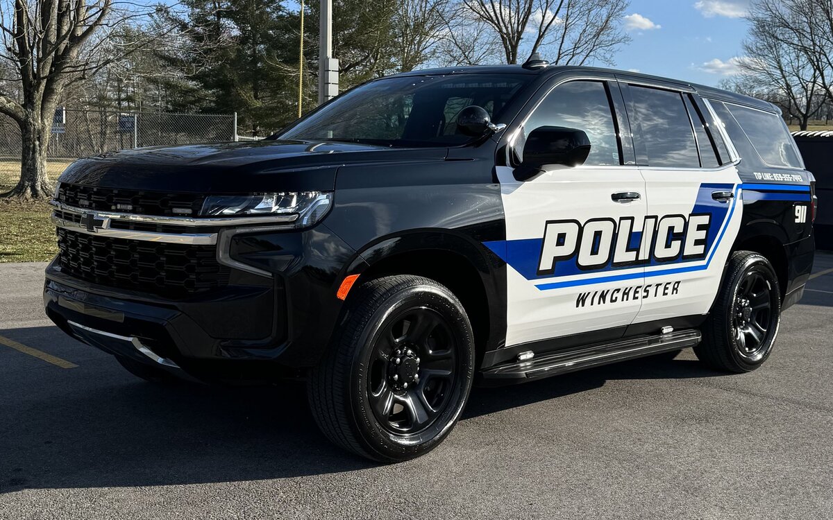 Black and white Winchester Police SUV parked outdoors in daylight. The vehicle has bold “POLICE” lettering on the side and emergency lights on top.