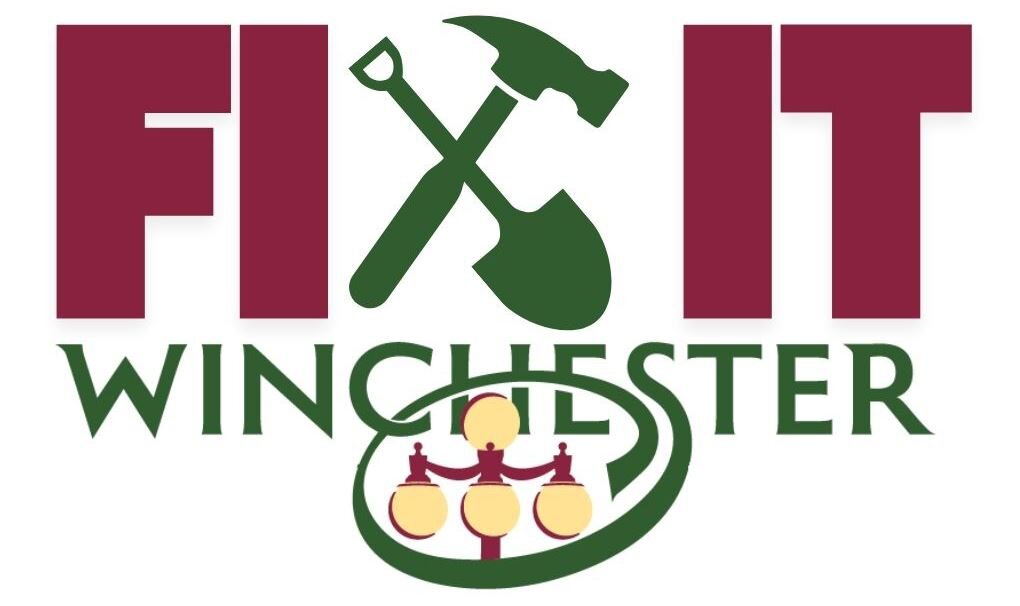 Logo for Fix It Winchester. The words 'FIX IT' are in large maroon letters with a green hammer and shovel crossed between them. Below, 'WINCHESTER' is written in green capital letters. A green oval surrounds an illustration of a decorative street lamp with four round lights.